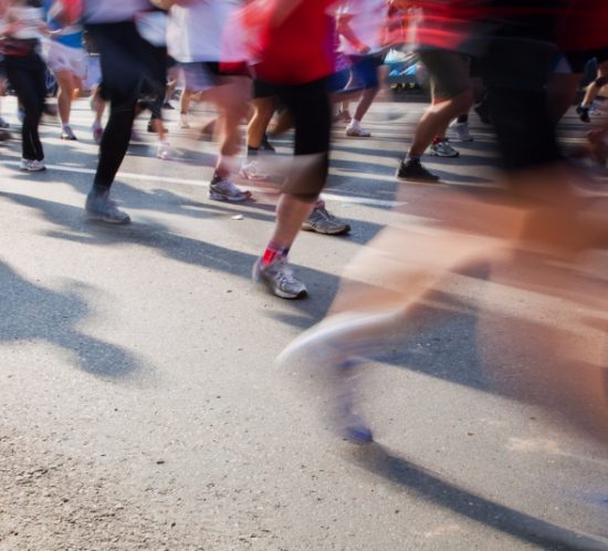 Running fast in marathon, legs close up. Sport, competition, energy.