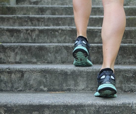 A runner running up the stairs, his feet are visible from back