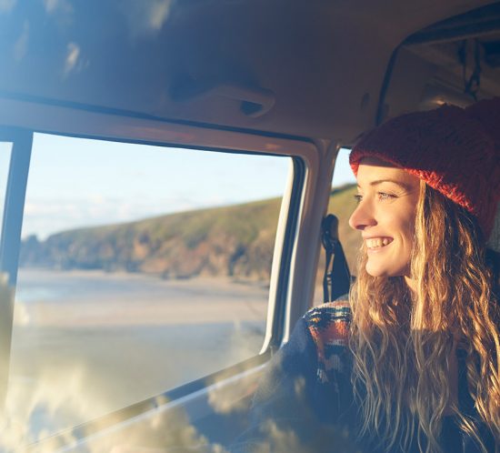 A smiled woman sitting on a bus and looking outside window