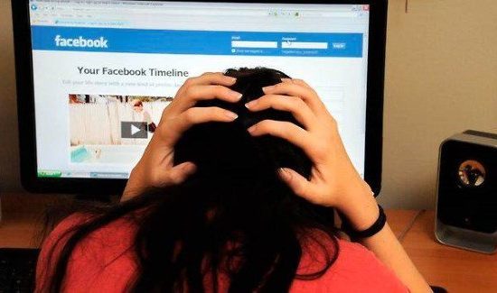 A woman sitting in front of a monitor and holding her had