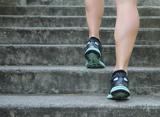 A runner running up the stairs, his feet are visible from back